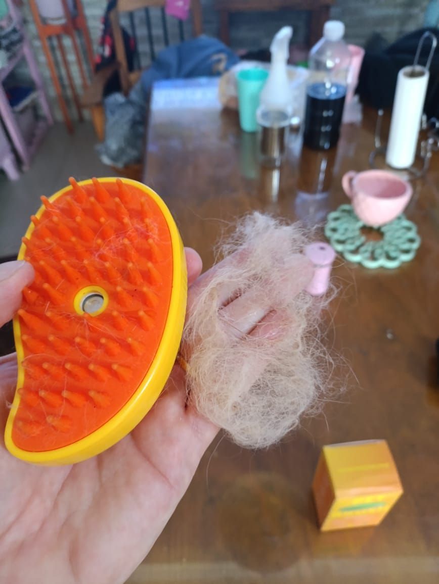 Cepillo para mascotas de color amarillo encima de una caja con la palabra 