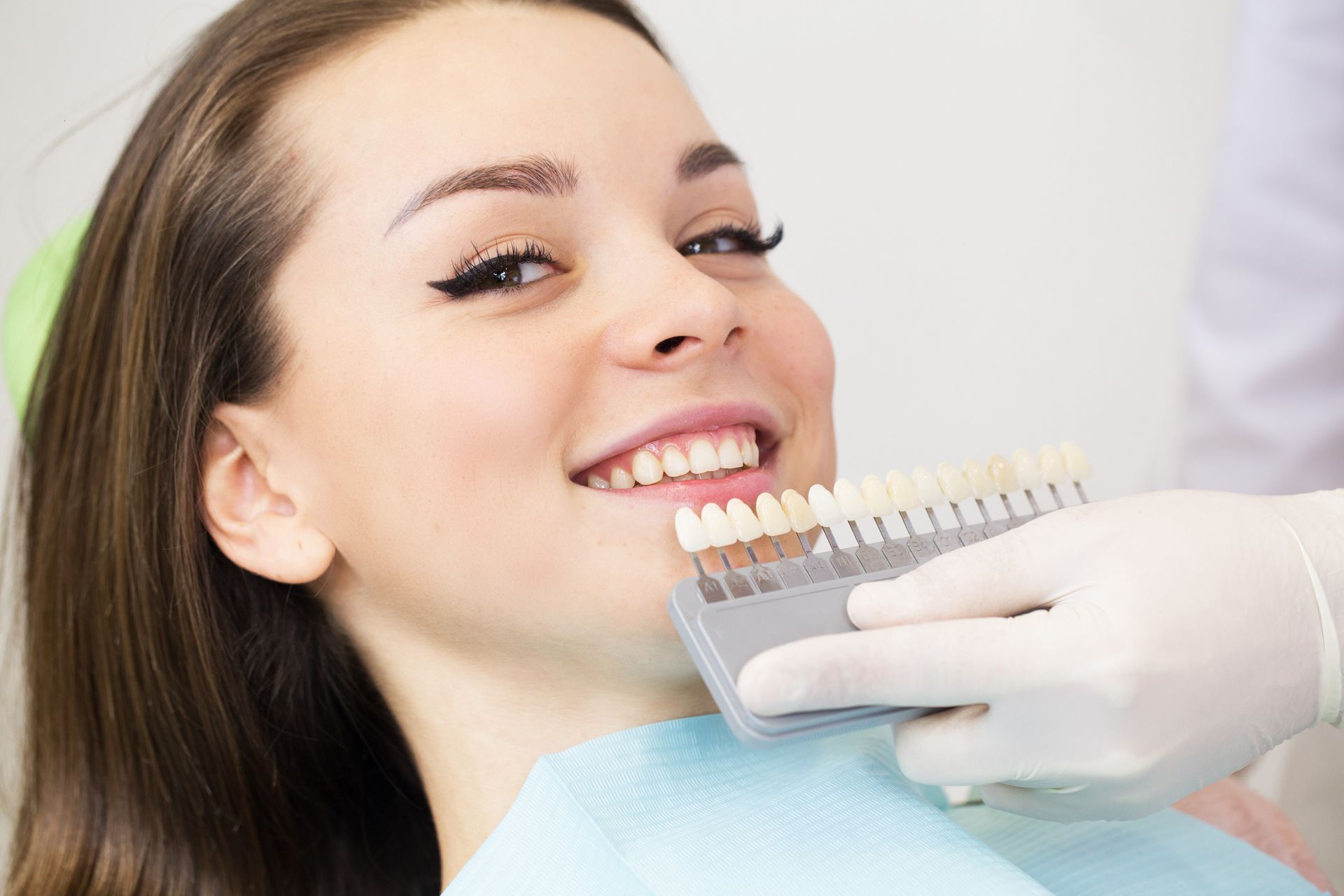 A woman smiling during a check-up, showing healthy teeth and dental care services.