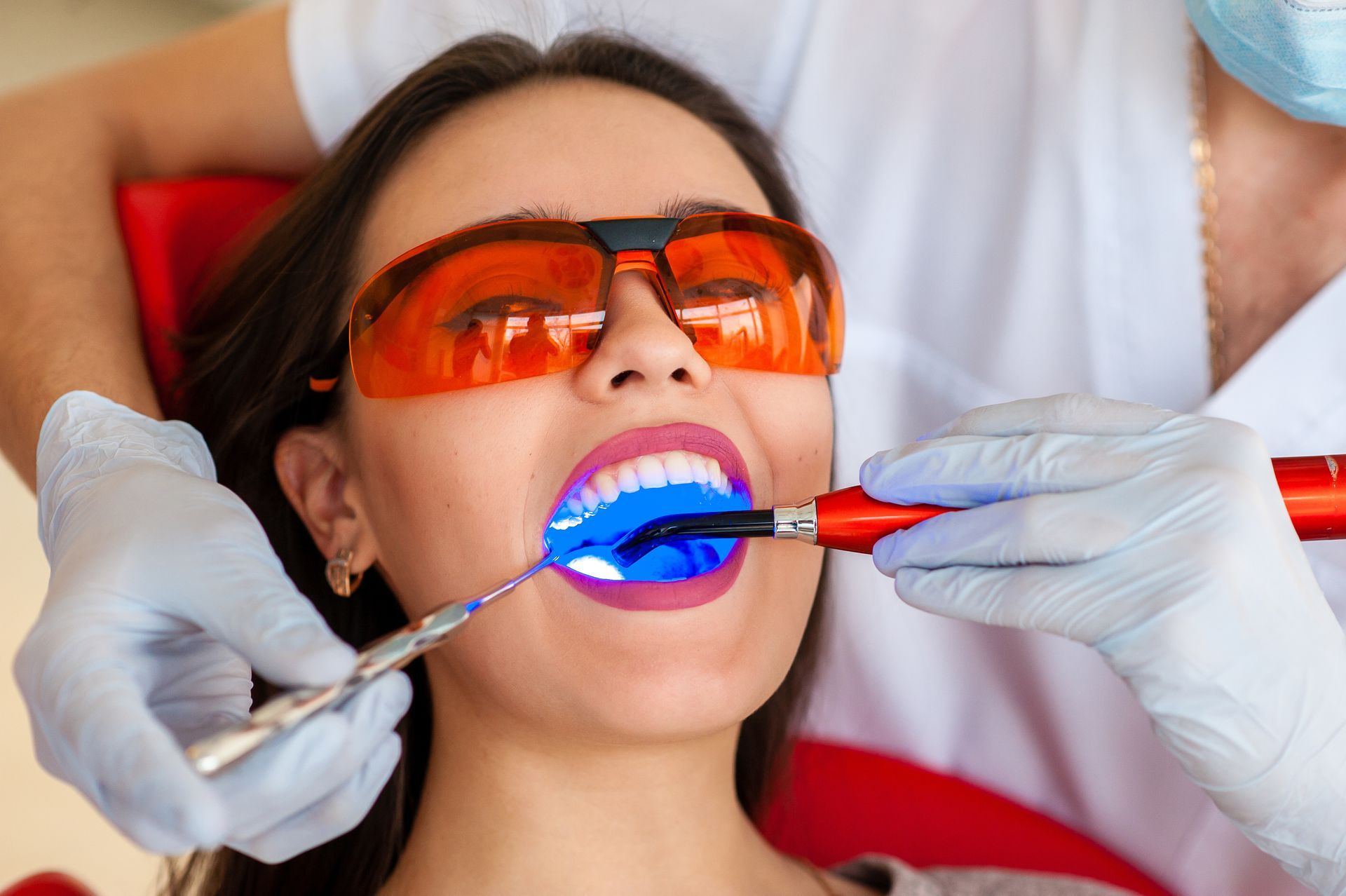 Cosmetic dentist performing professional teeth whitening treatment on a patient.