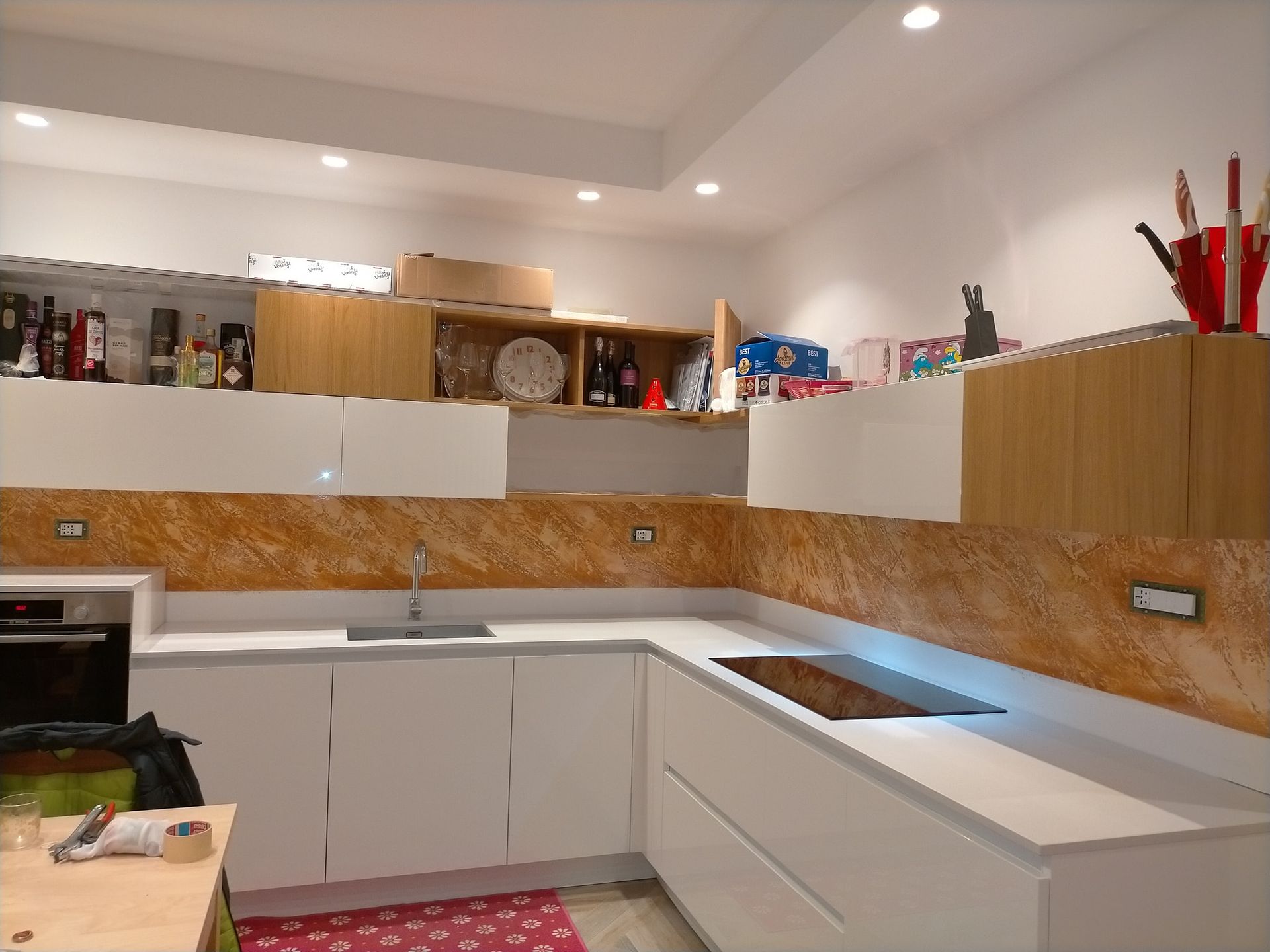 Una cucina con mobili bianchi e il muro in microcemento