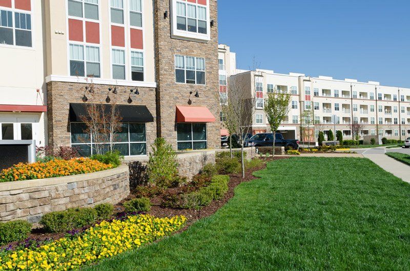 A large apartment building with a lush green lawn in front of it.