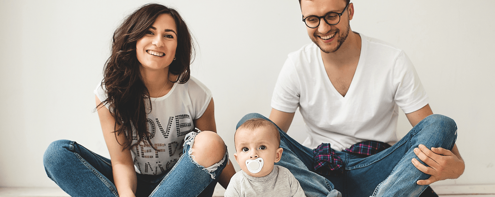 A man and a woman are sitting on the floor with a baby.