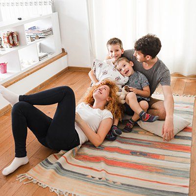 A family is laying on a rug on the floor in a living room.