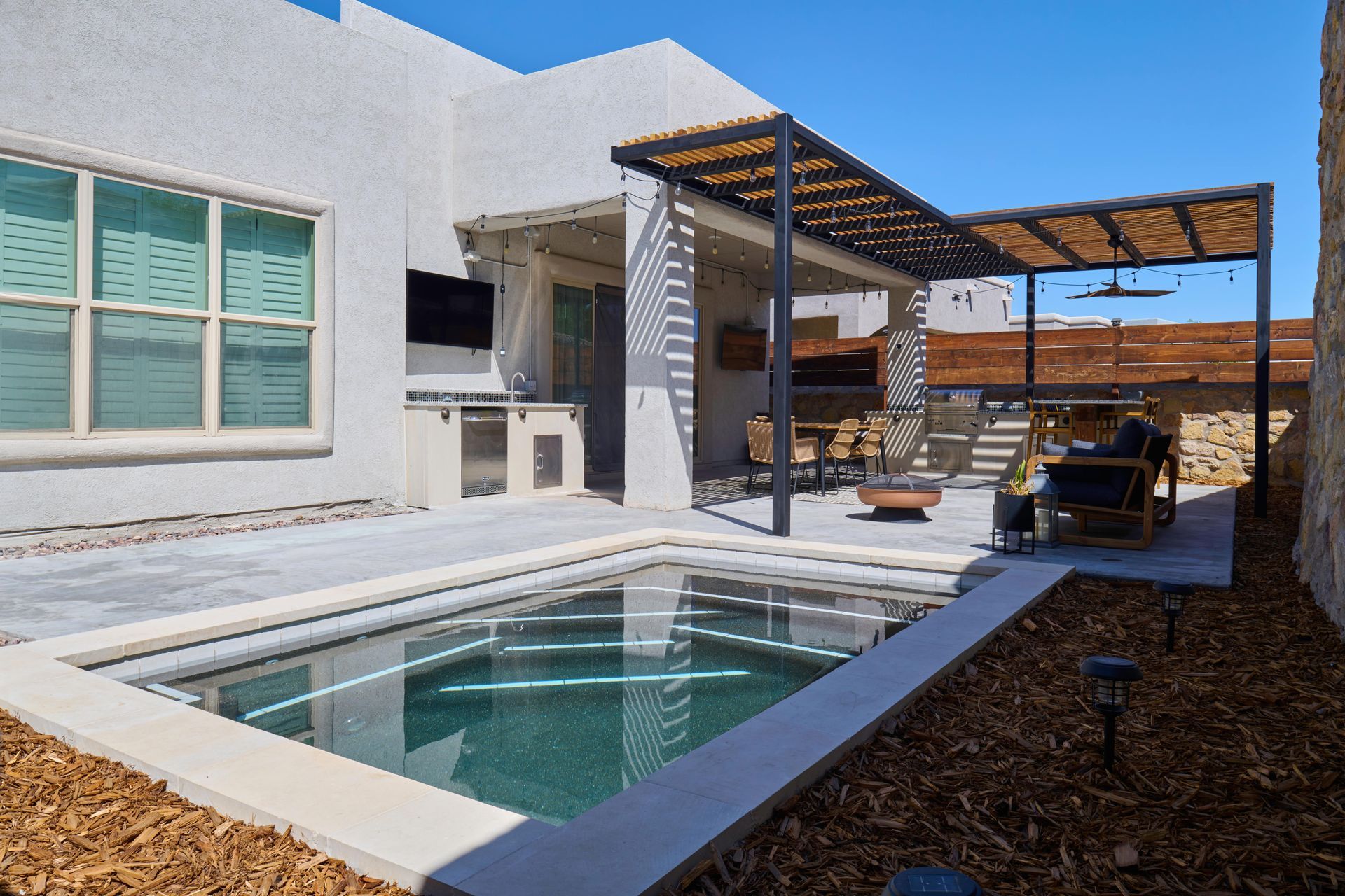 Backyard with small pool, patio with pergola, outdoor kitchen, and fire pit.