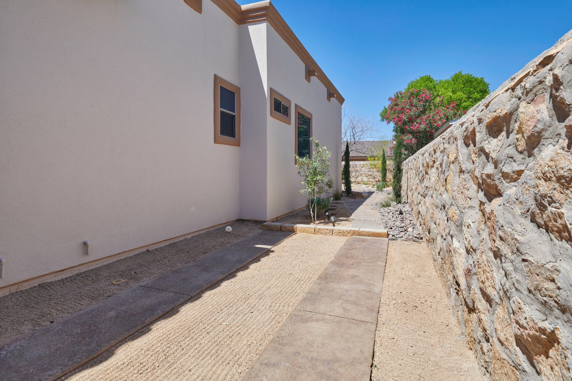 Exterior view of a building with stone wall and a walkway with gravel.