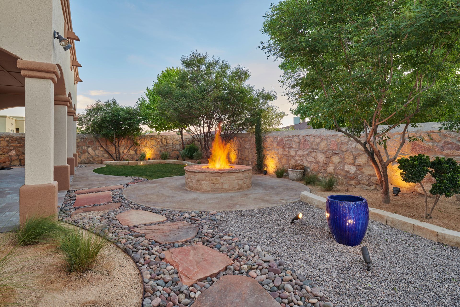 Backyard with a fire pit, stepping stones, and blue ceramic pot.