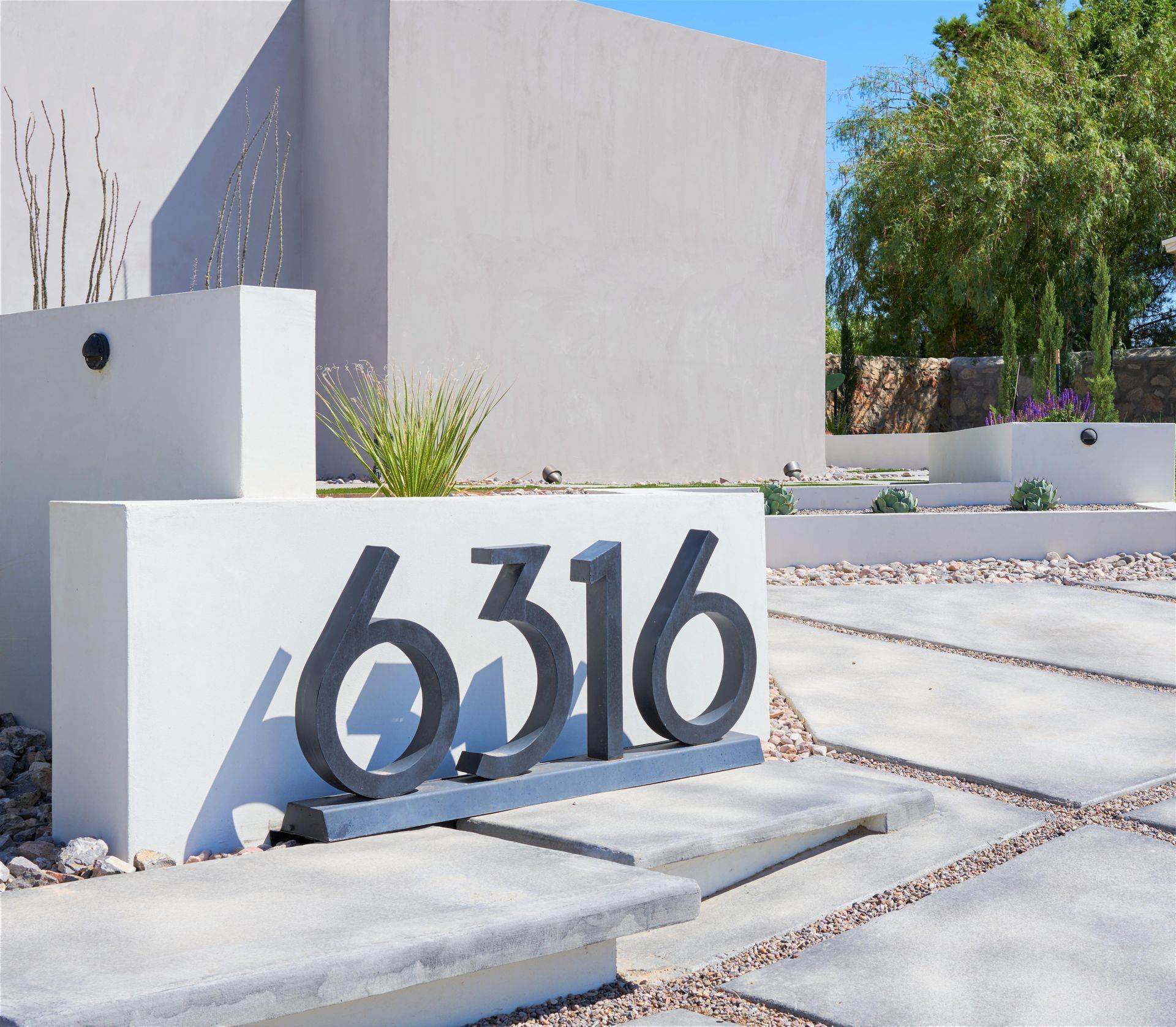 Modern home exterior with address 6316 in large, dark numbers on a white wall.
