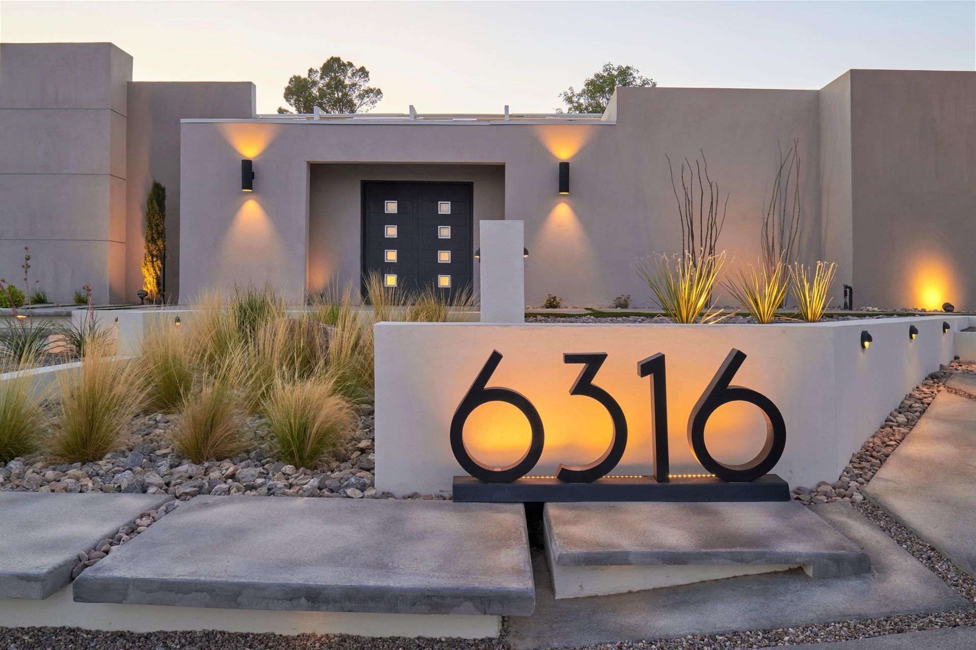 Modern home exterior with address 6316 in black numbers, lit up.