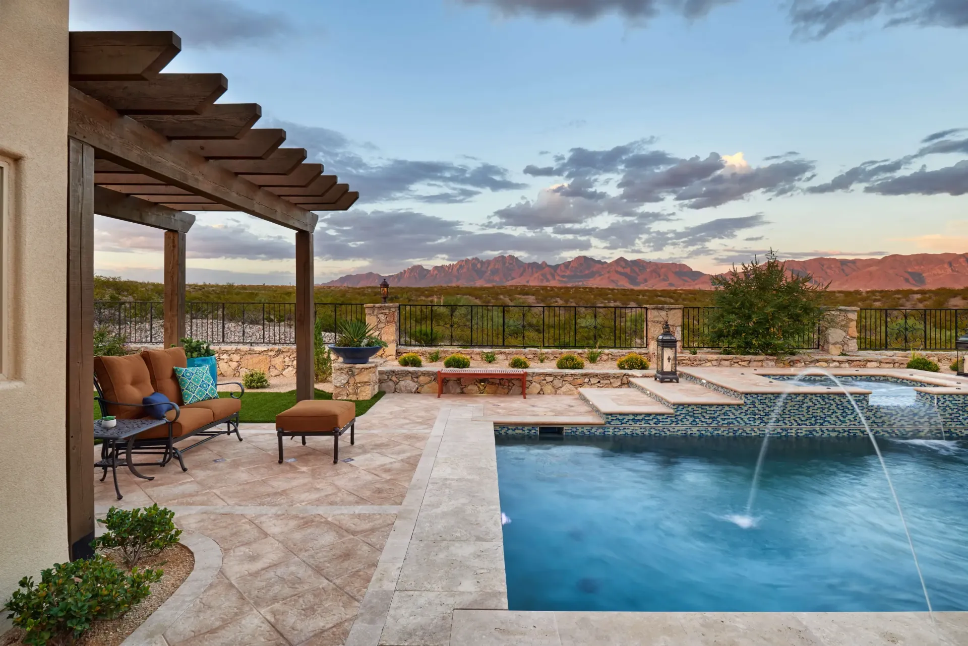 Patio with pool and pergola, view of mountains at dusk.
