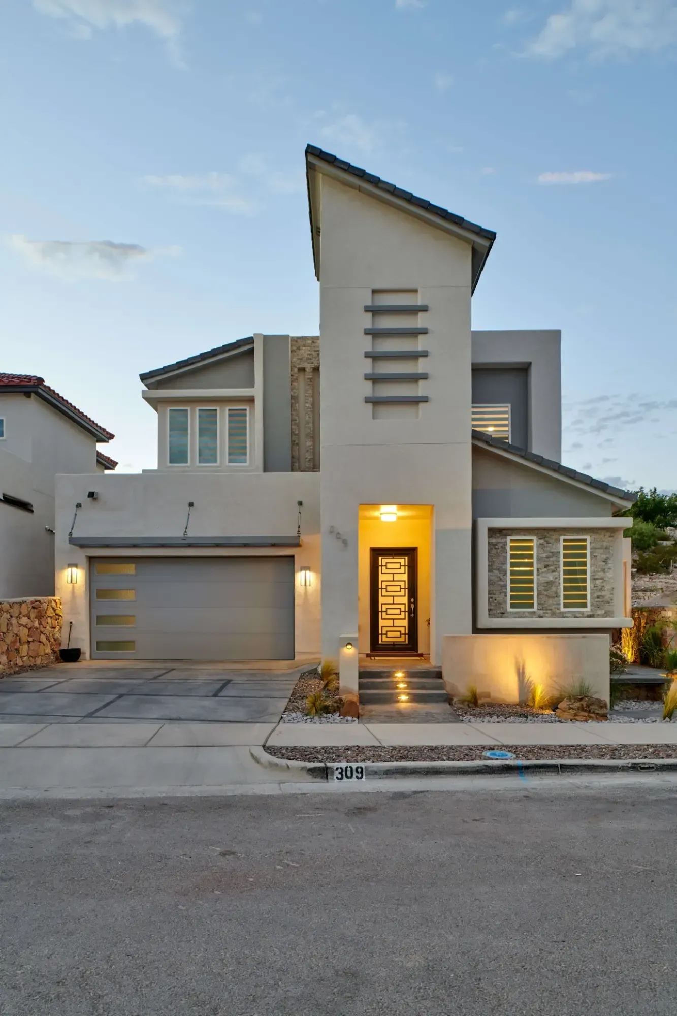 Modern two-story house with gray and white exterior, arched entry, and garage.