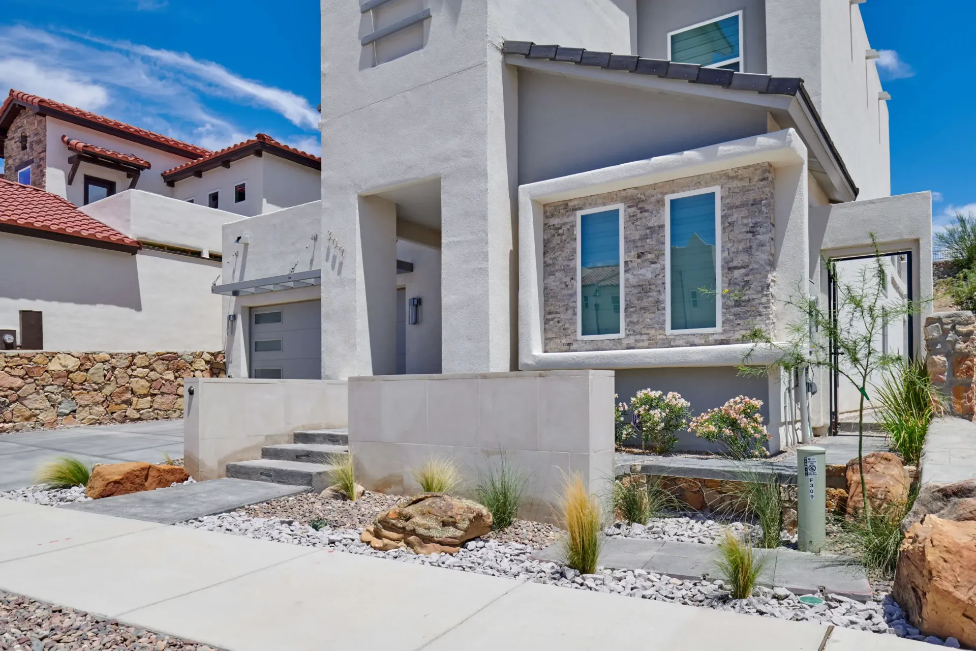 Modern house exterior with stucco walls, stone accents, and drought-tolerant landscaping.