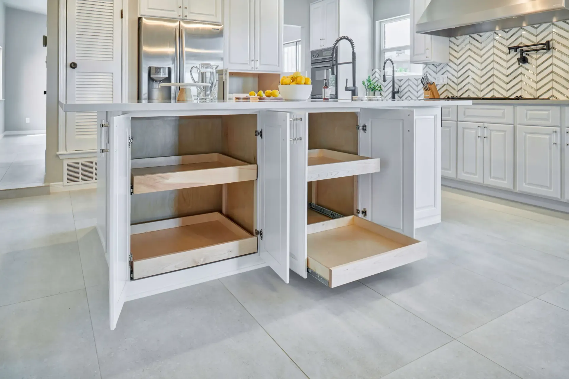 White kitchen island with open pull-out shelves, showcasing storage. Light wood interiors.