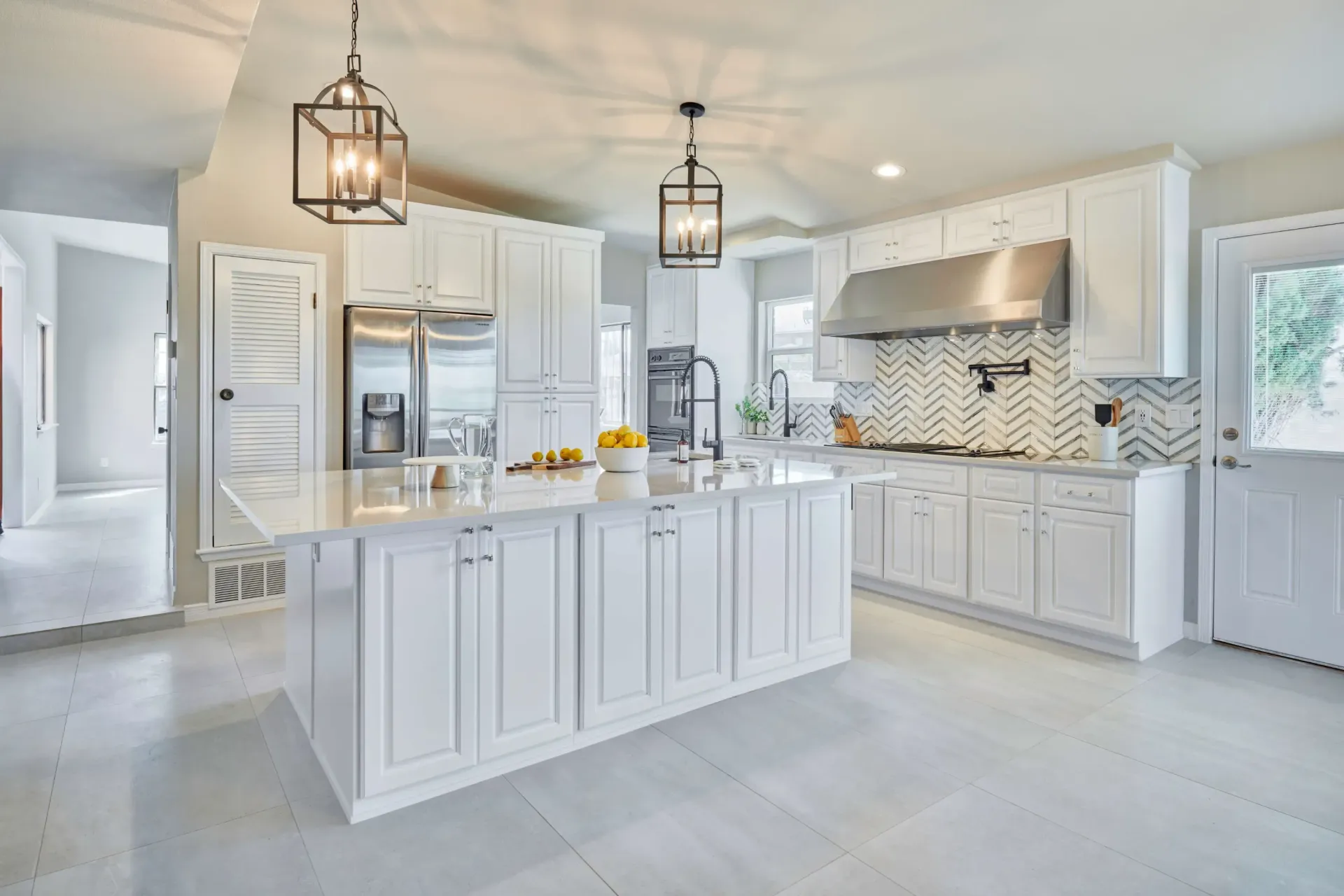 White kitchen with an island, cabinets, and stainless steel appliances.
