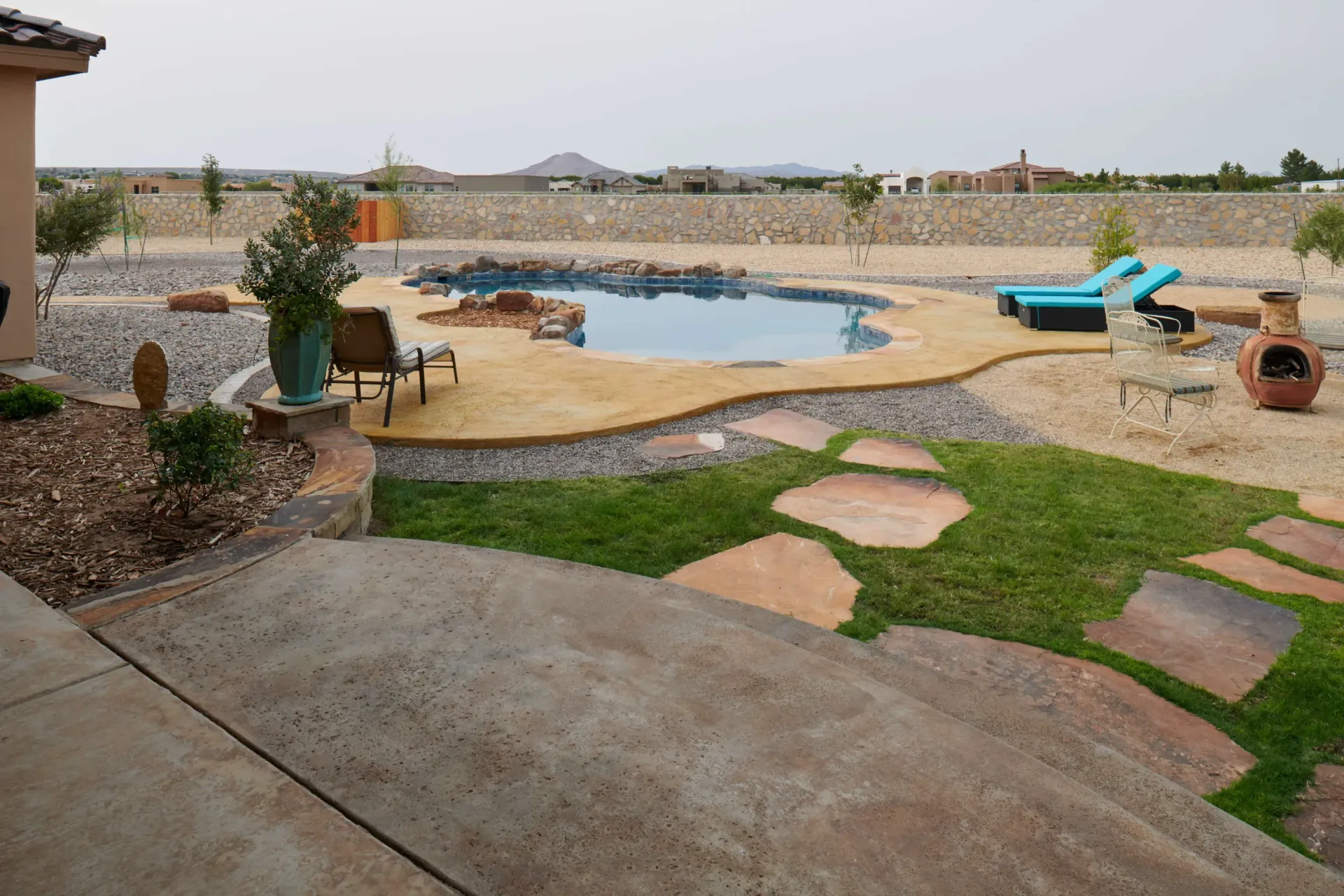Backyard with pool, lounge chairs, and desert landscaping.