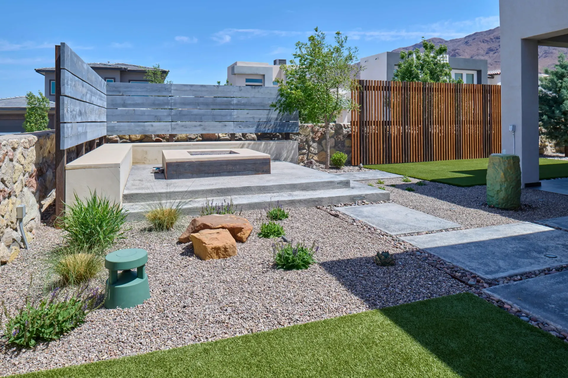 Outdoor patio with fire pit, seating, stone walkway, and gravel landscaping.