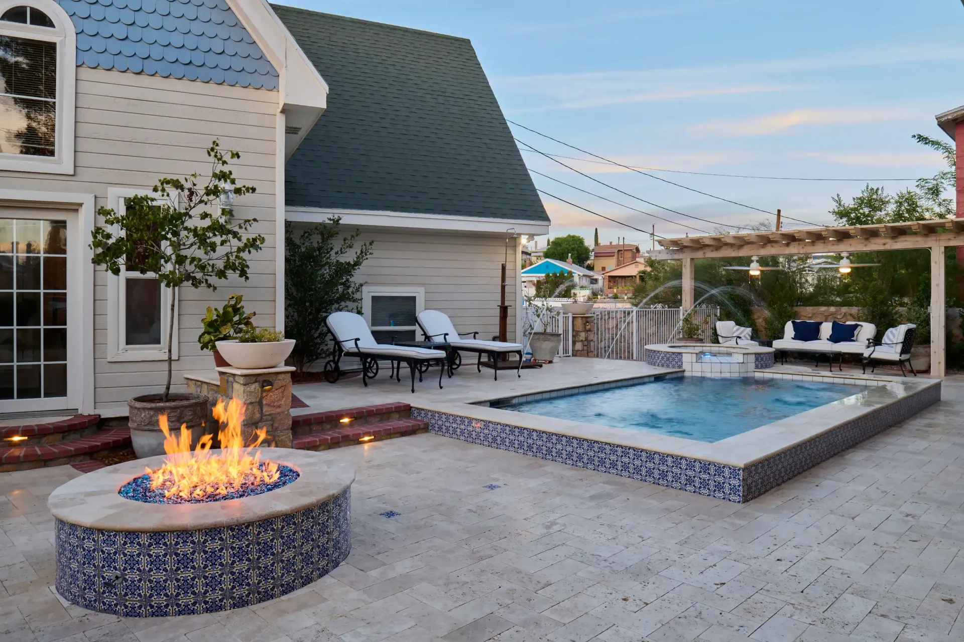 Backyard patio with fire pit, pool, lounge chairs, and pergola with seating.