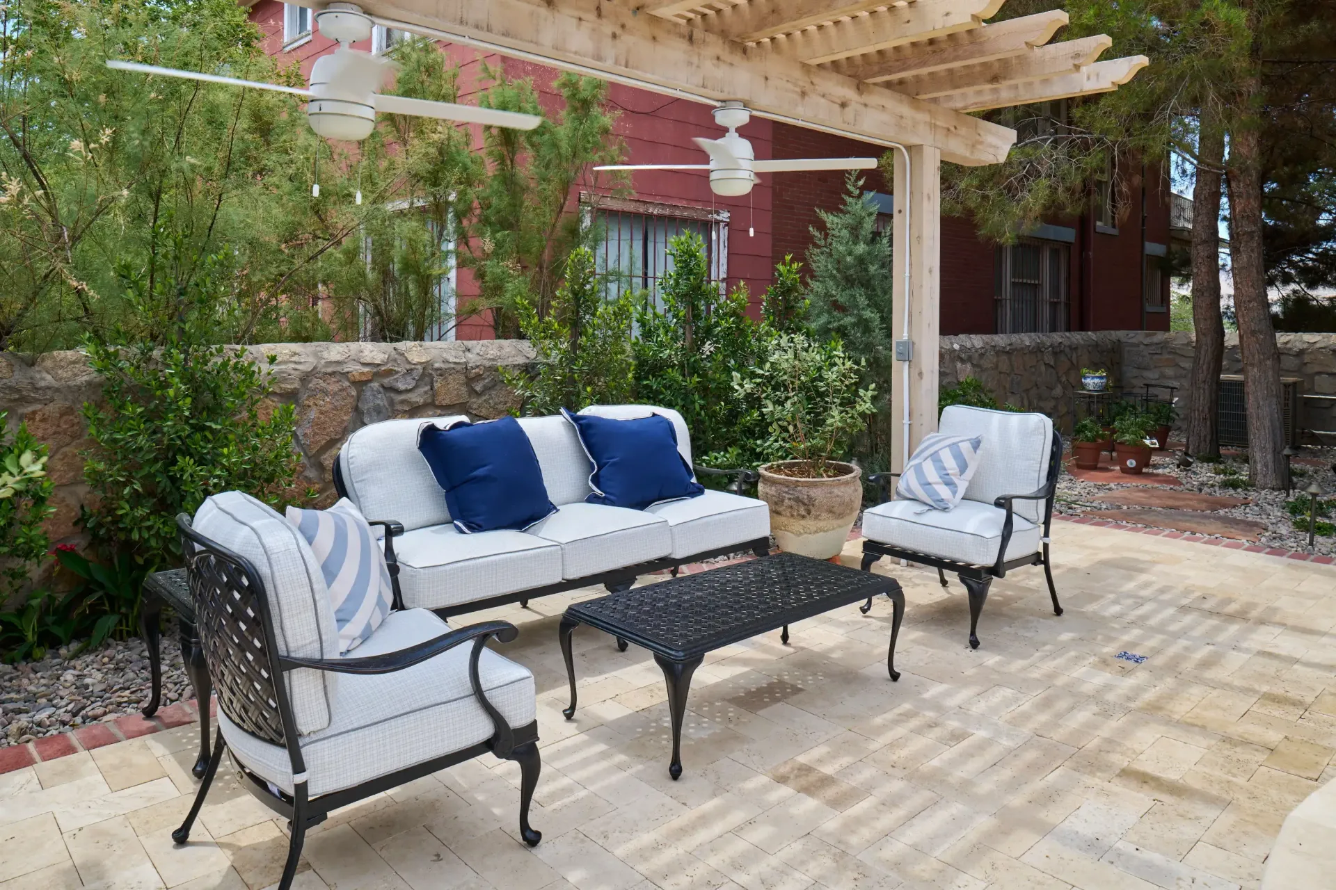 Outdoor patio with furniture under a wooden pergola, brick patio.