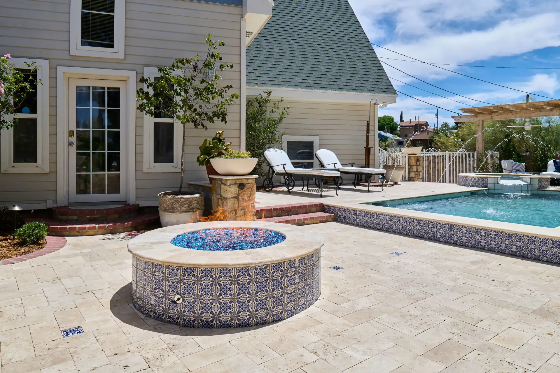 Backyard patio with fire pit, pool, and house. Blue and tan color scheme.