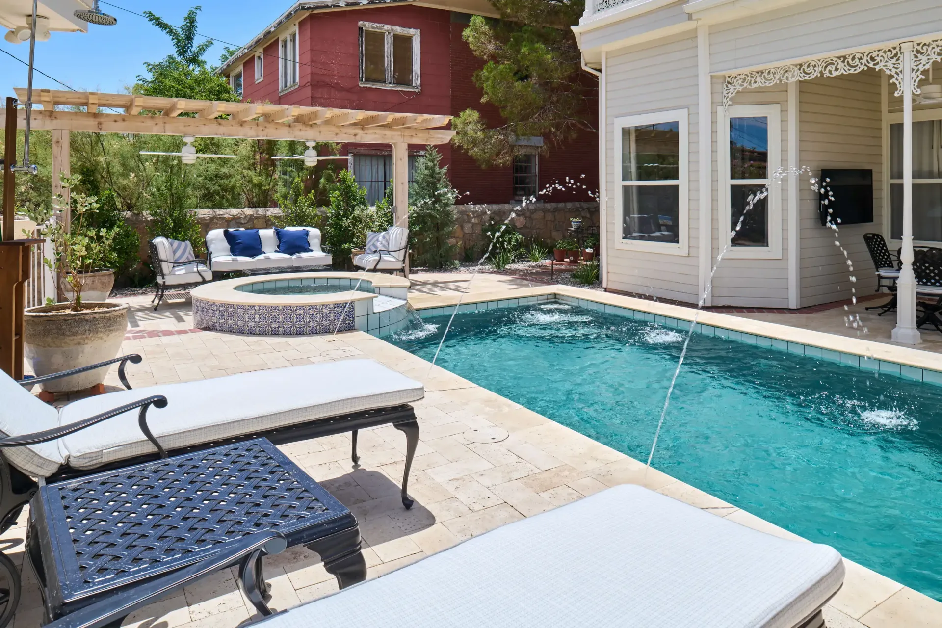 Pool area with pool, hot tub, lounge chairs, and building.