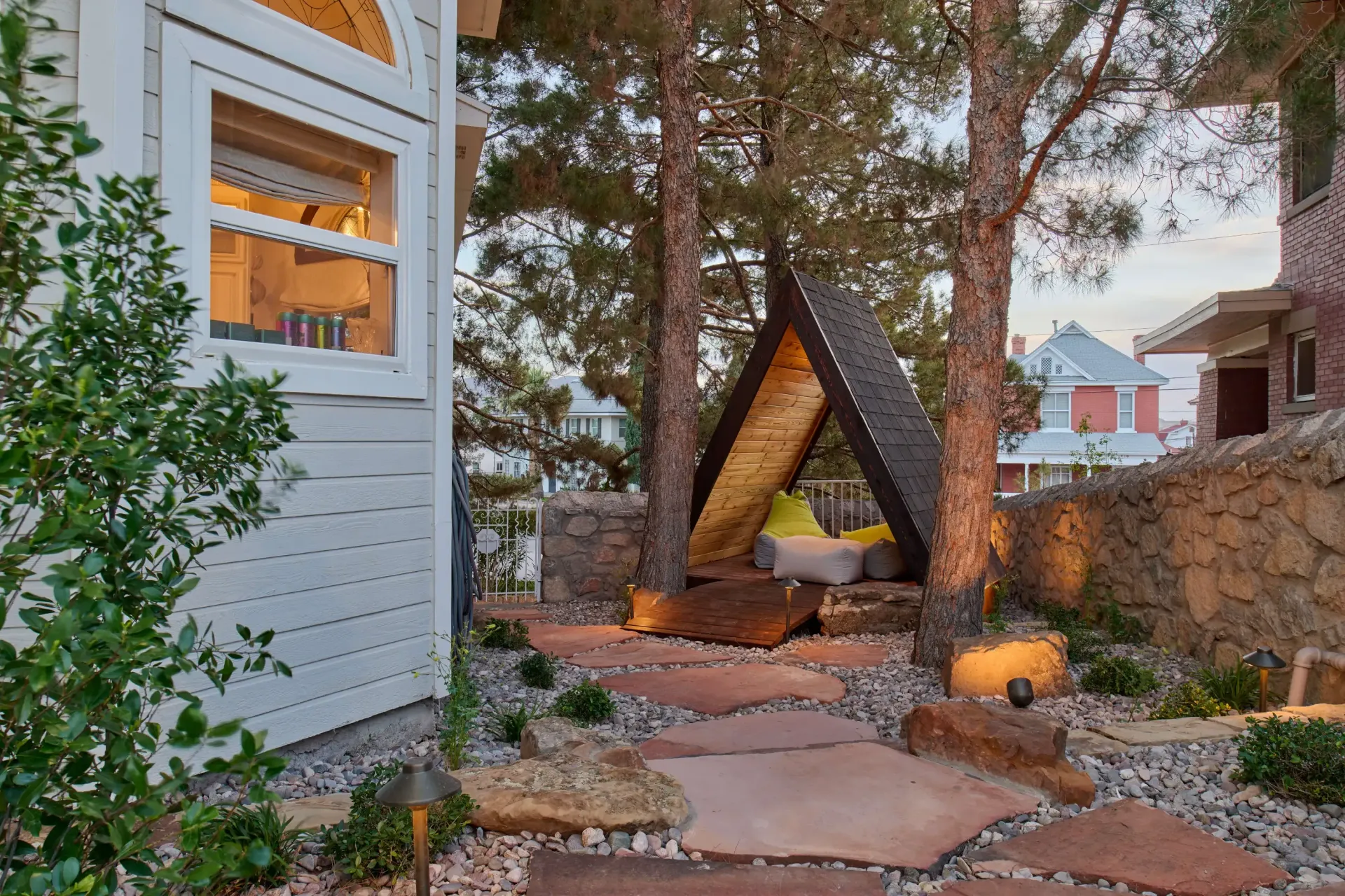 Outdoor seating area with A-frame shelter, stone path, and trees.