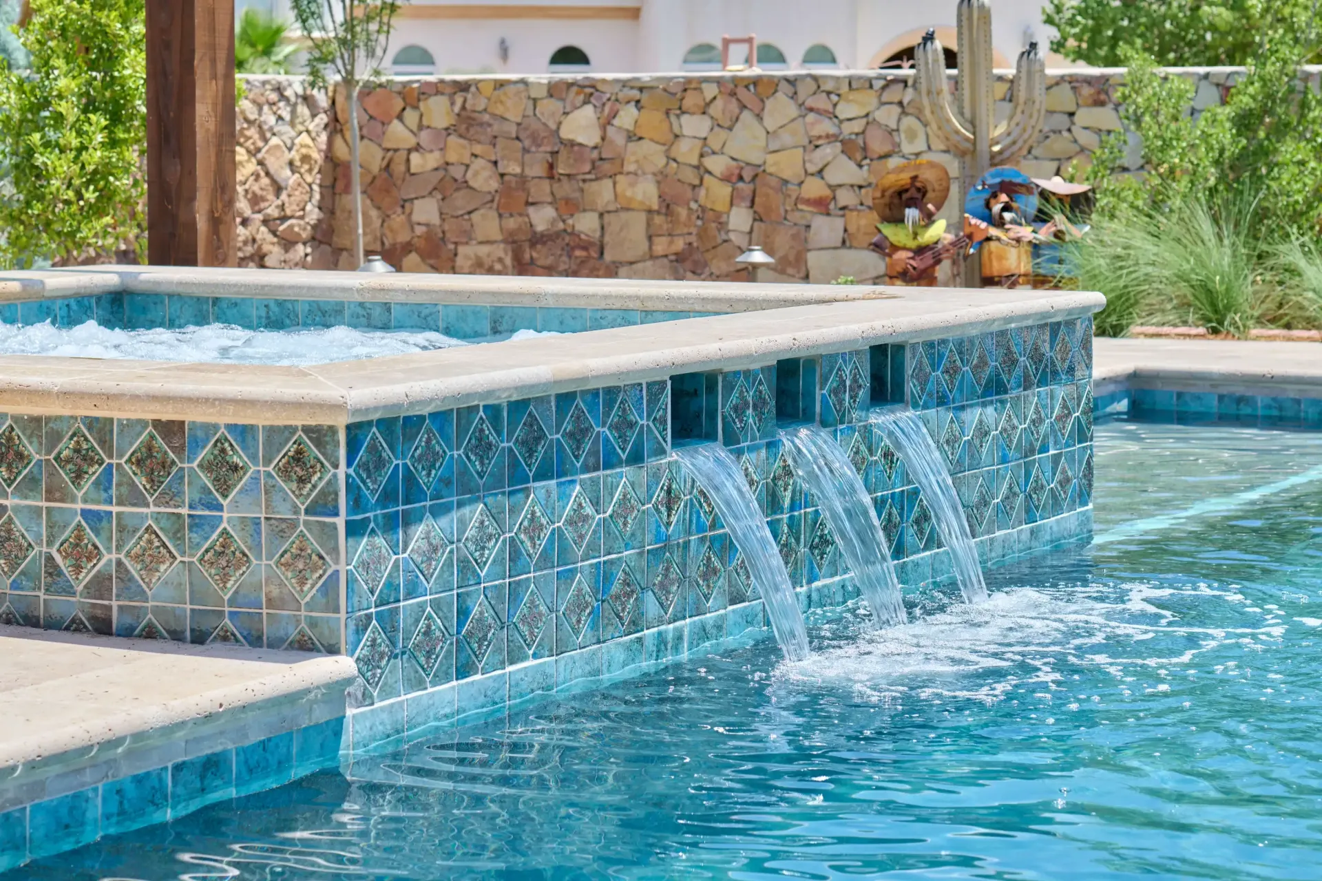 Pool with blue tiled wall, cascading water, and decorative tiles.