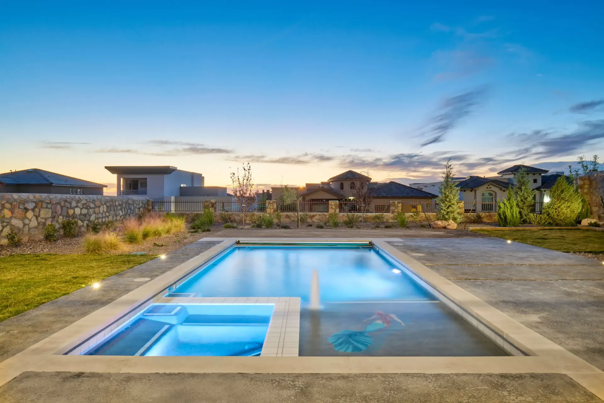 Backyard pool and spa with evening sky in a suburban setting.