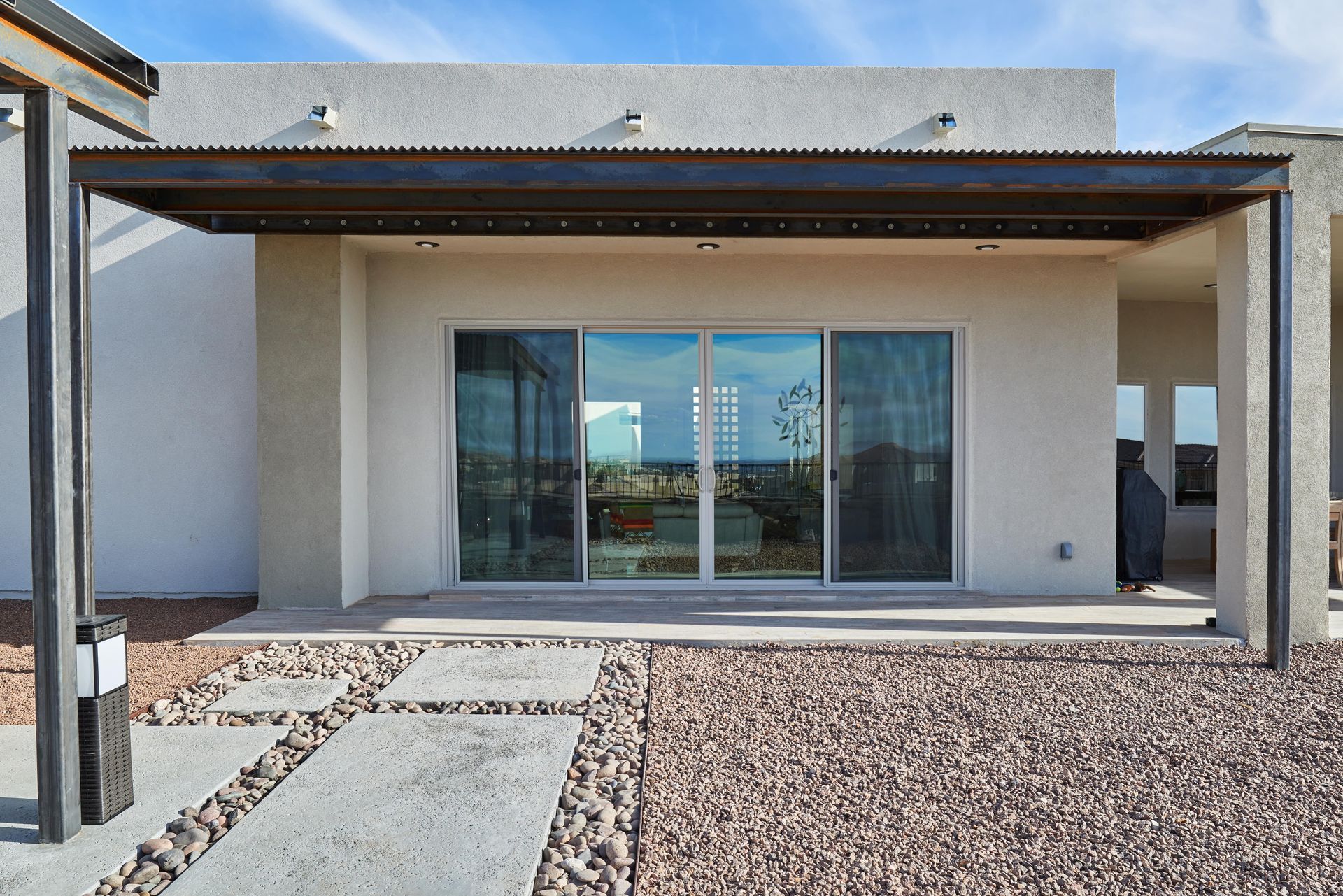 Back patio with sliding glass doors, overhead pergola, and stone path.