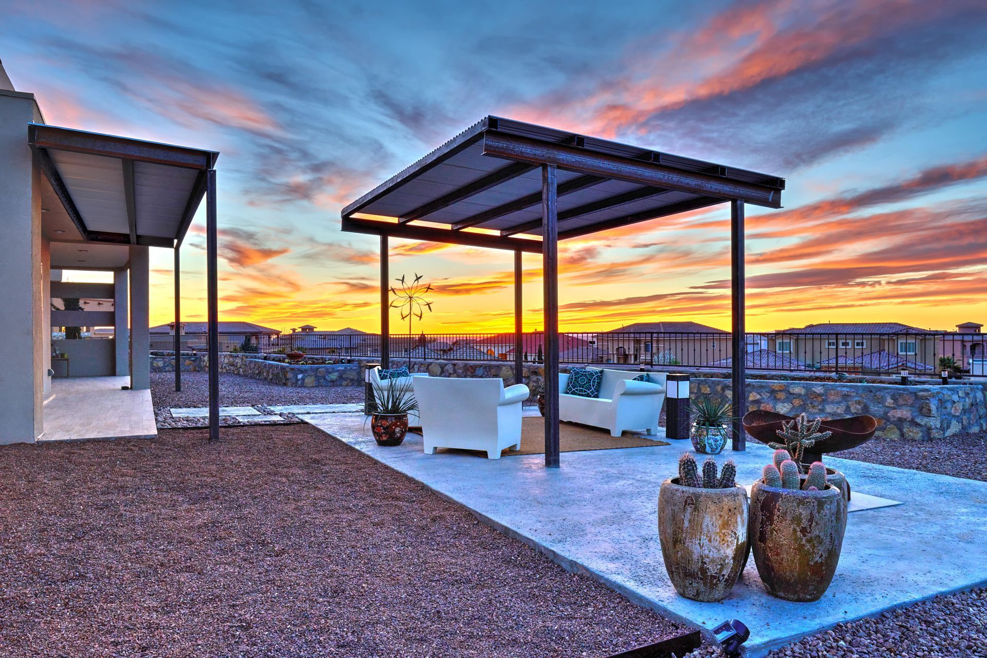 Rooftop patio with seating, metal canopy, and sunset in the background.