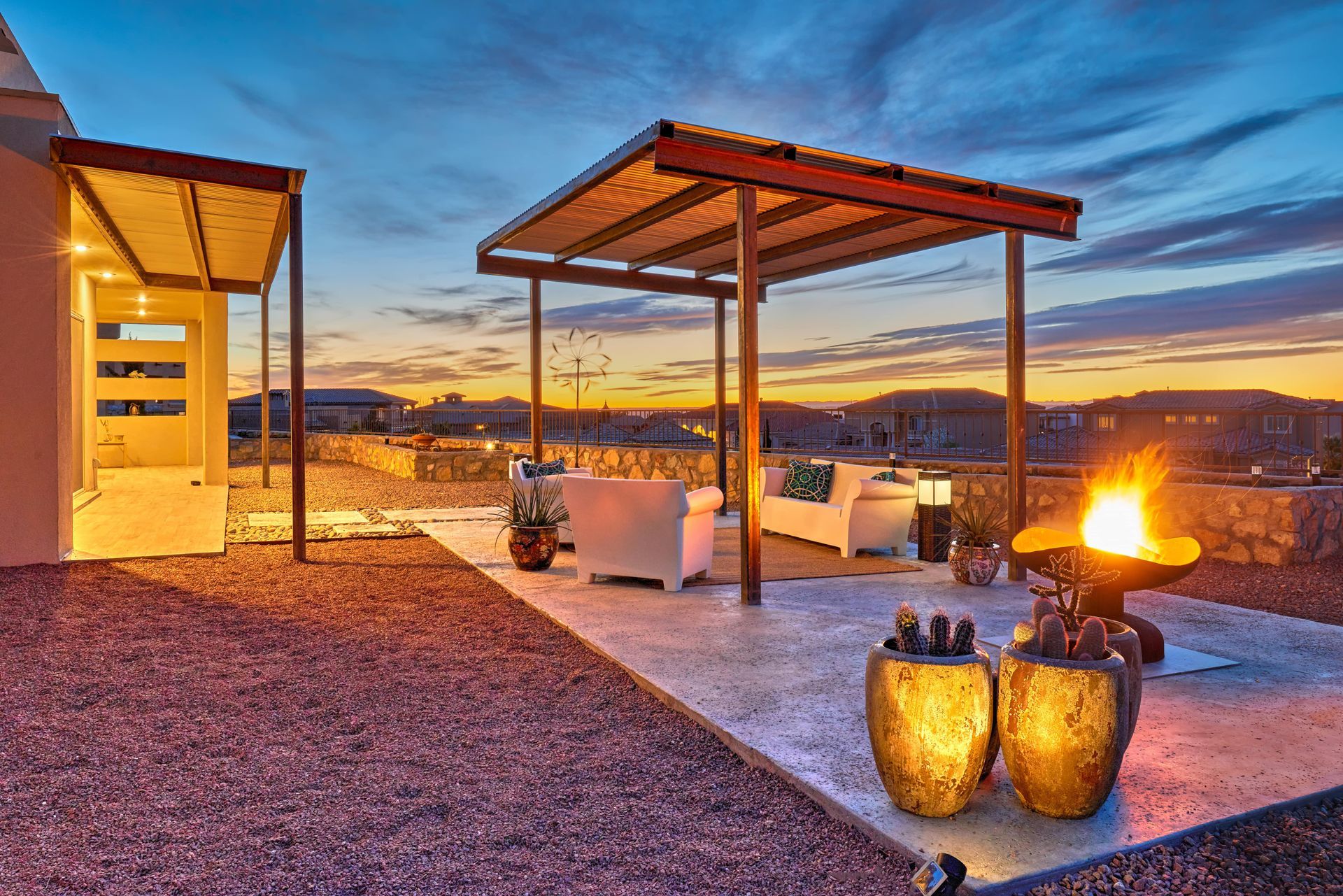 Outdoor patio with a fire pit, seating under a pergola, and evening sky.