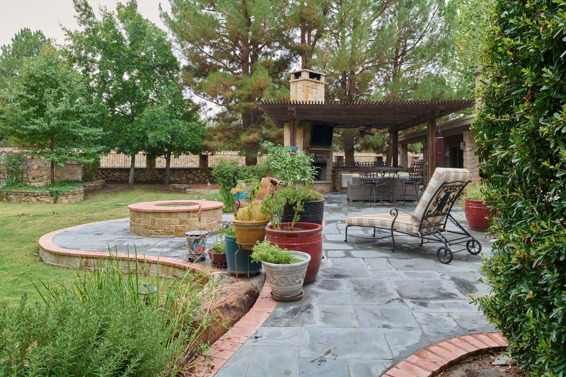 Backyard patio with fire pit, seating, and pergola with outdoor fireplace.