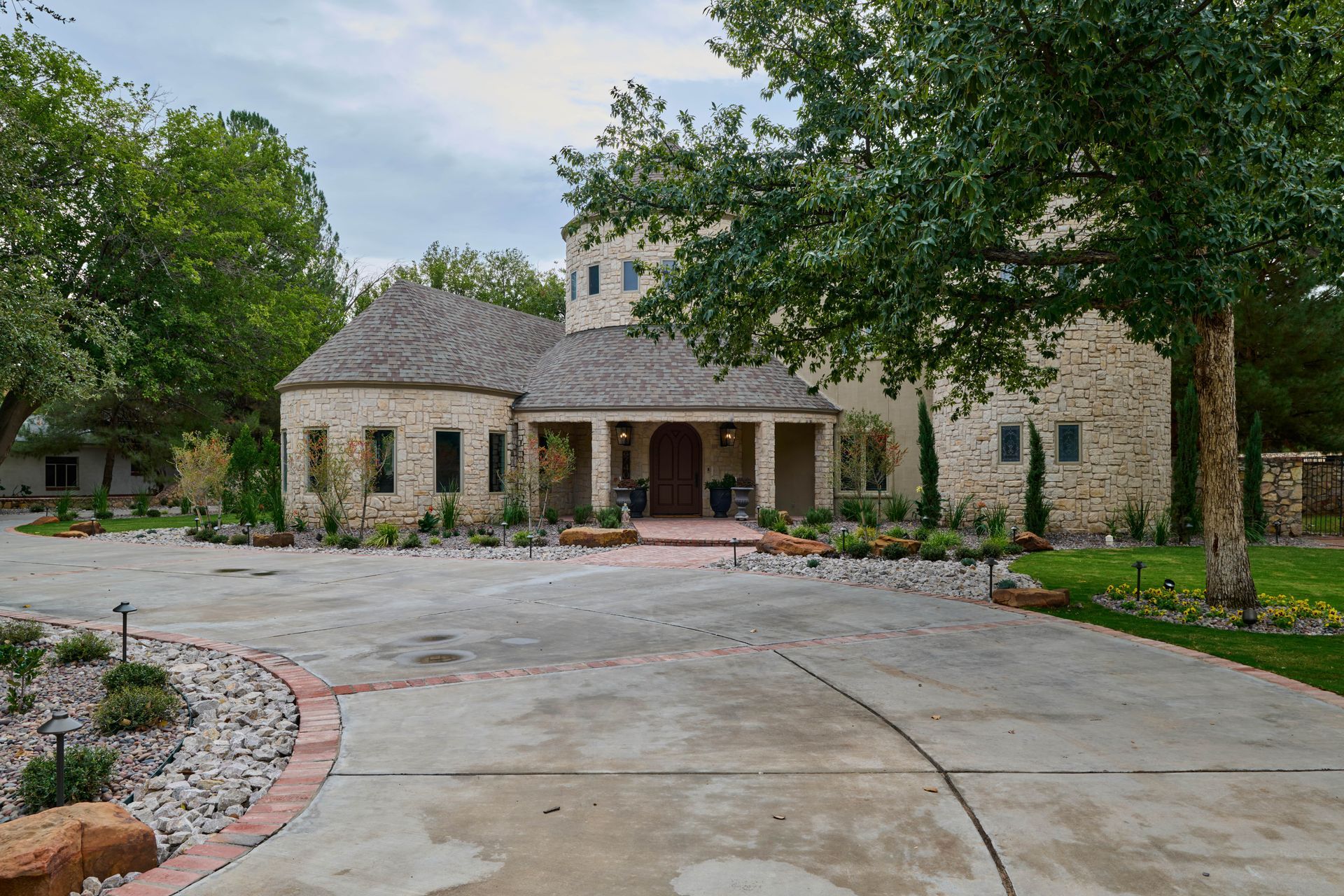 Stone house with circular tower, arched entryway, and circular driveway.