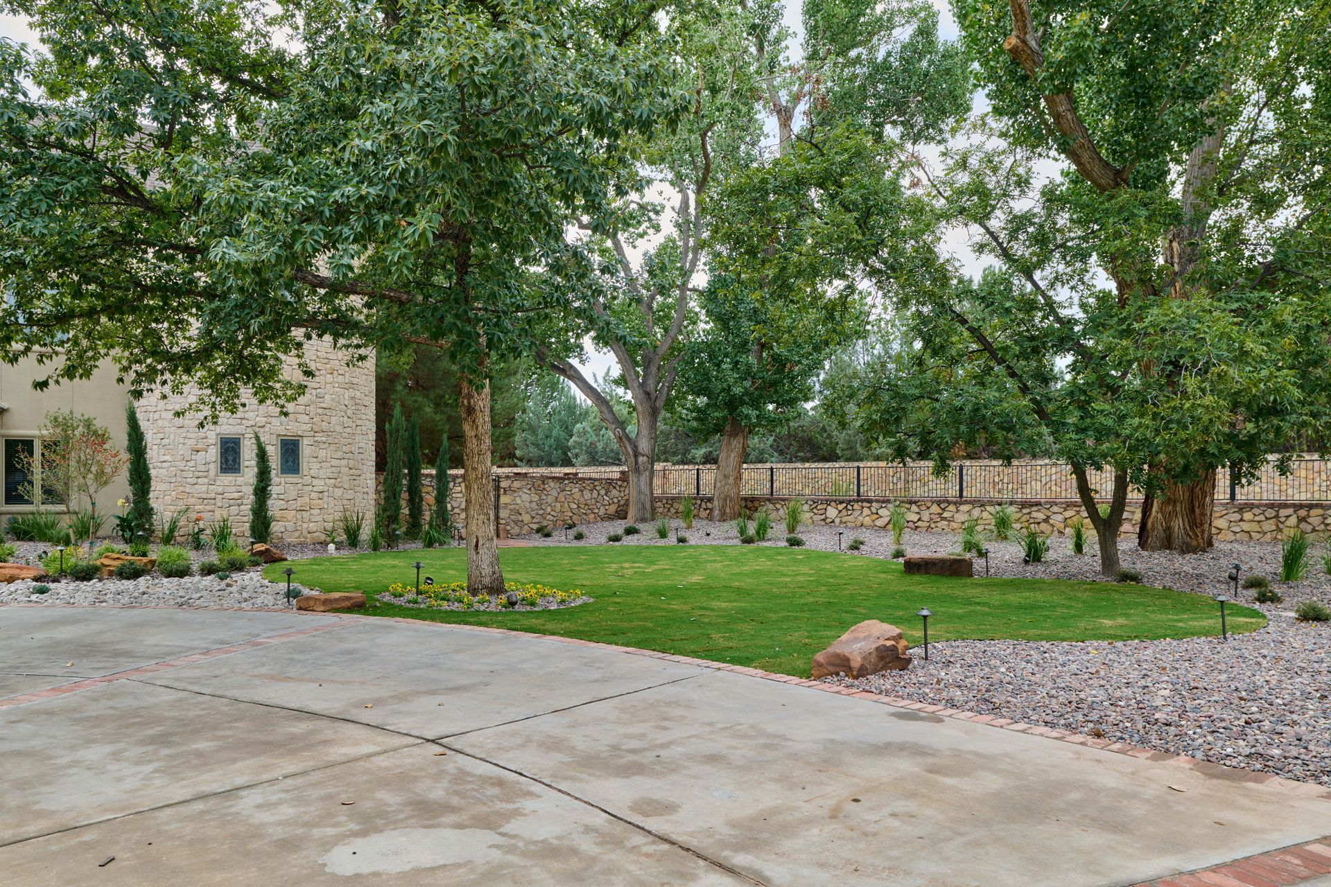 Exterior view of house and yard with trees, lawn, gravel, and a concrete driveway.