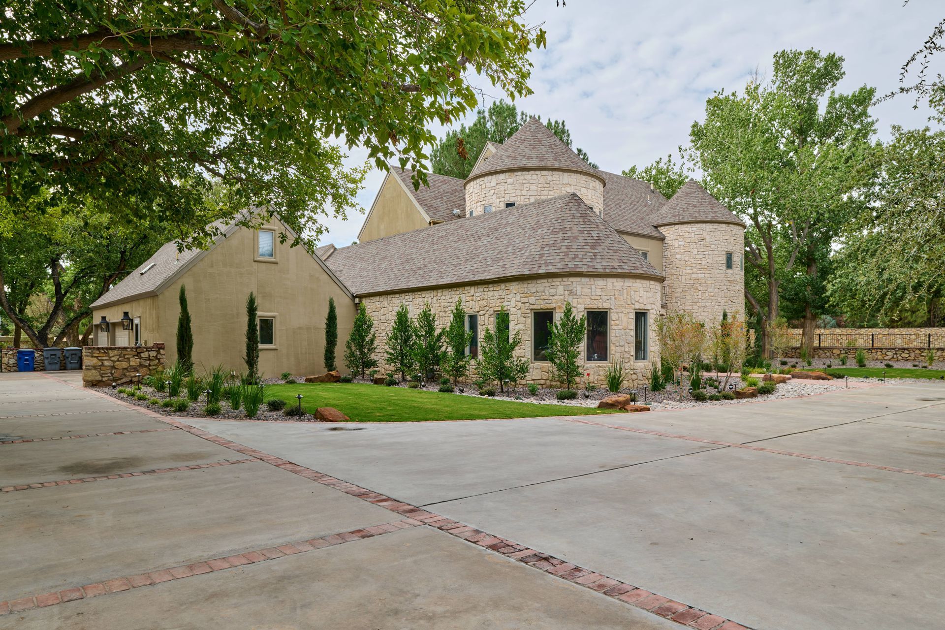 Stone and stucco house with multiple round turrets and a wide driveway.