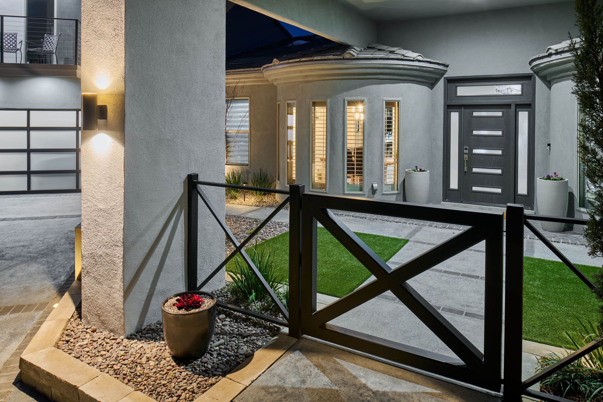 Modern gray house exterior with black gate, grass, and stone pathway.