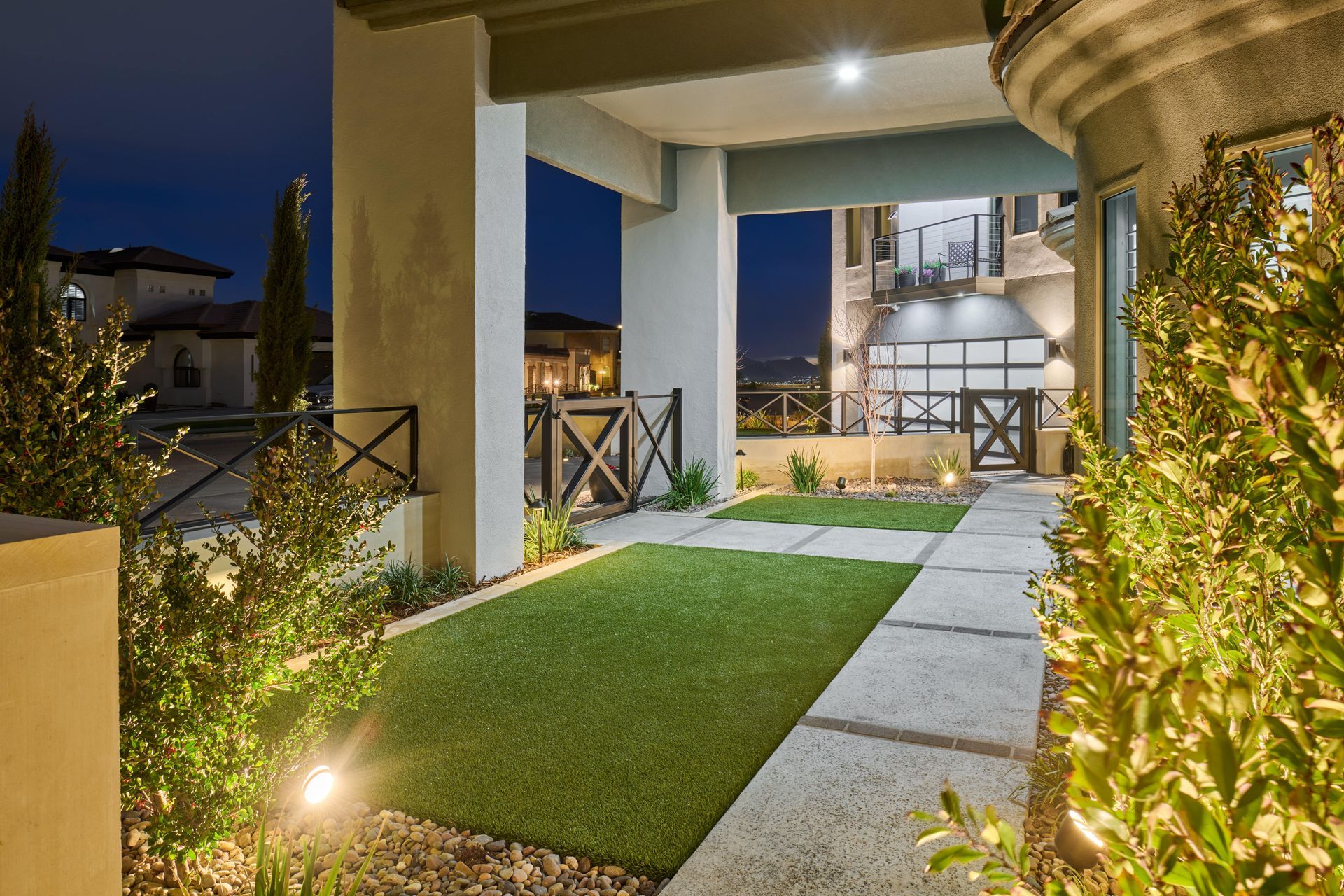 Entrance of a house lit at night with artificial grass and garden.