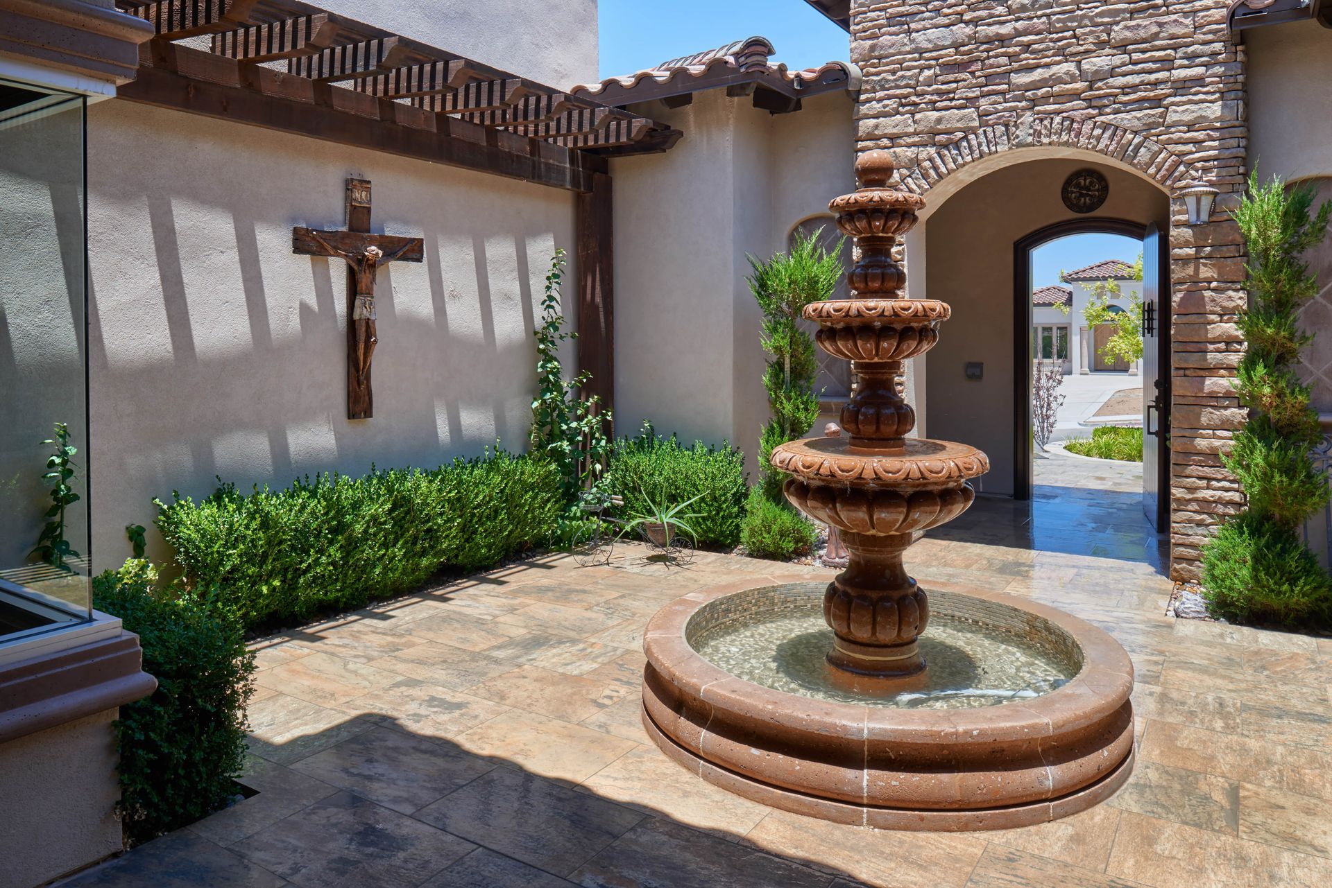 Courtyard with tiered fountain, cross, and arched doorway.