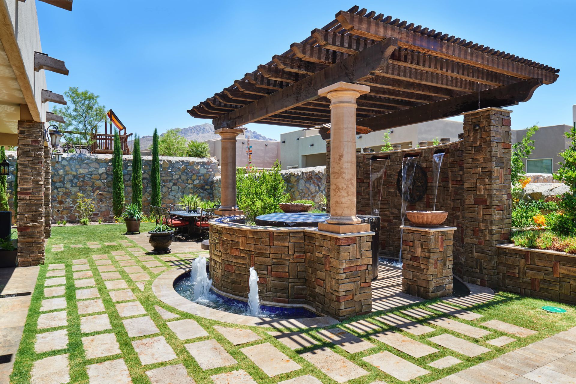 Backyard with stone waterfall feature, pergola, and grassy lawn.