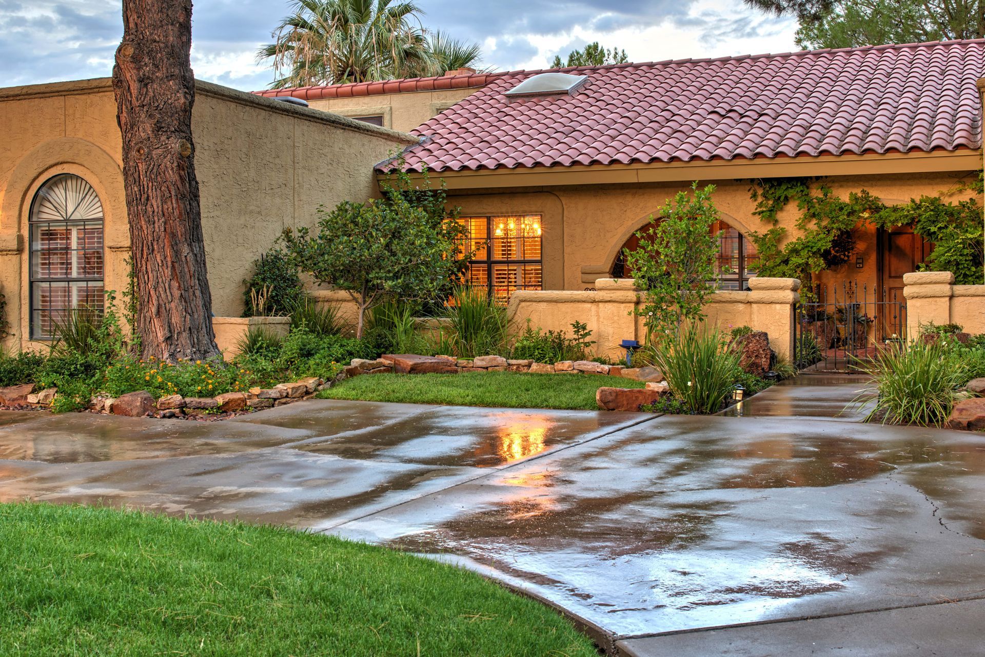 Spanish-style house with red tile roof, arched windows, and wet driveway.
