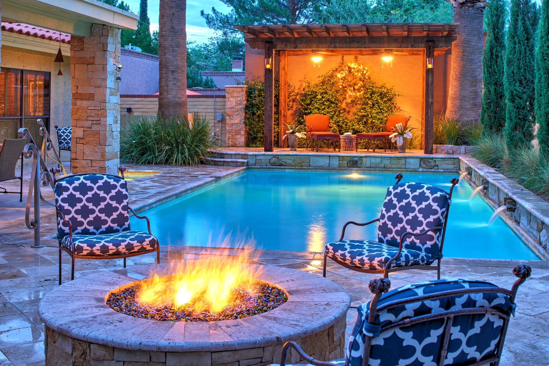 Backyard pool with fire pit and lounge seating under a pergola.