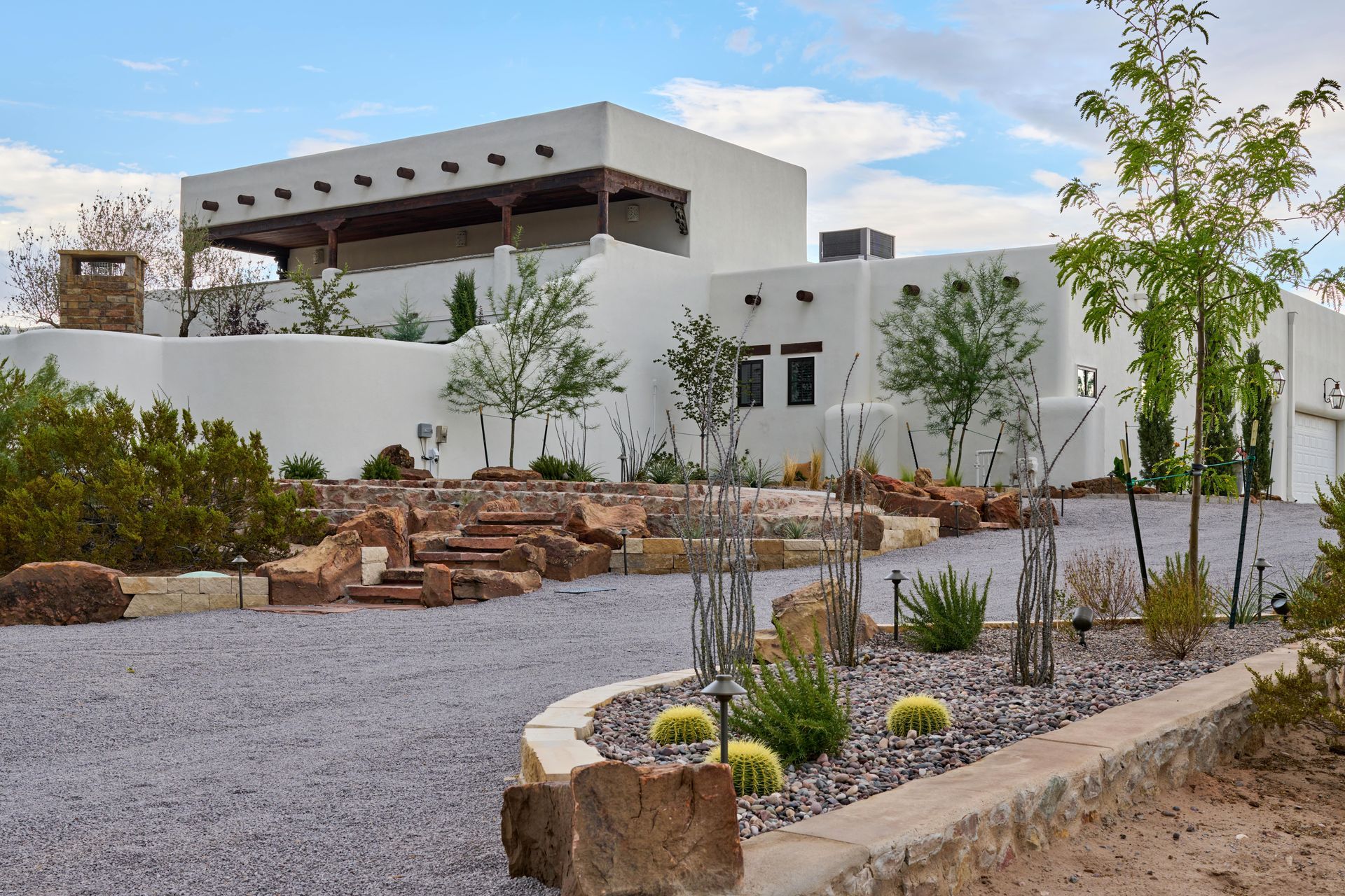 White stucco southwestern style house with flat roof, gravel driveway, and desert landscaping.