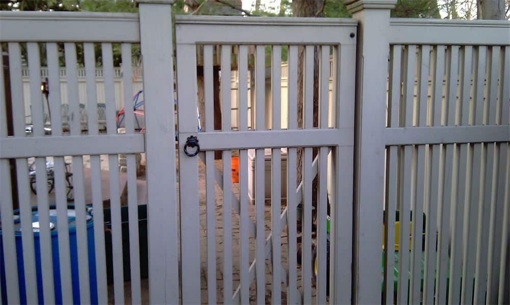 White picket fence gate with latch, providing access to a backyard.