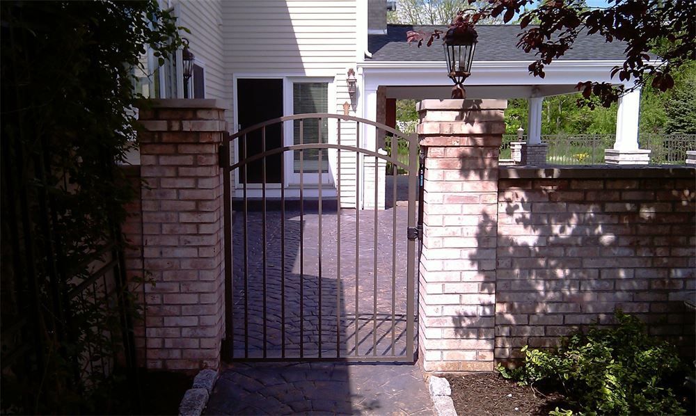 Brick gate and pillars in front of a house. The gate is made of dark metal.