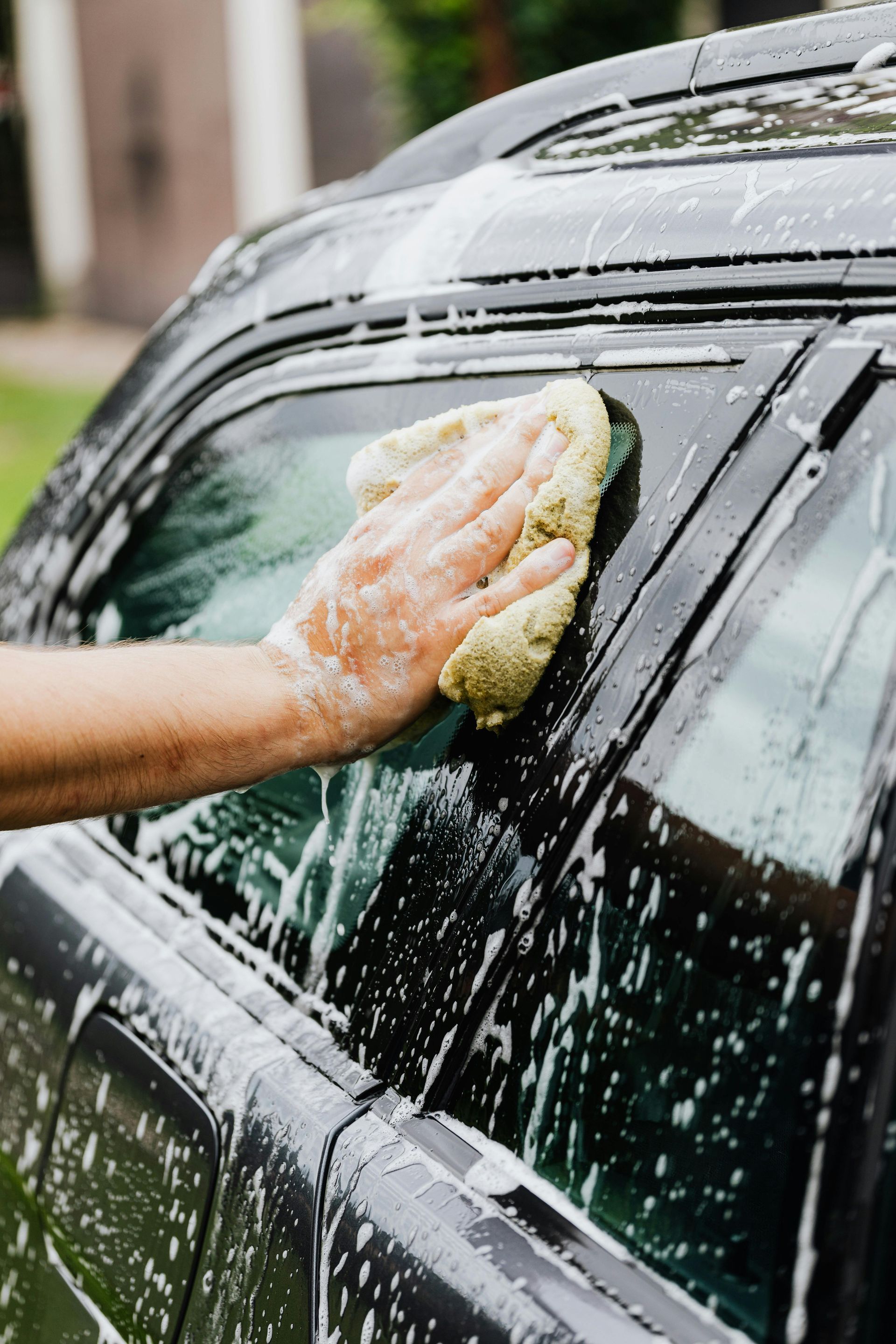 A person is washing a car with a sponge.