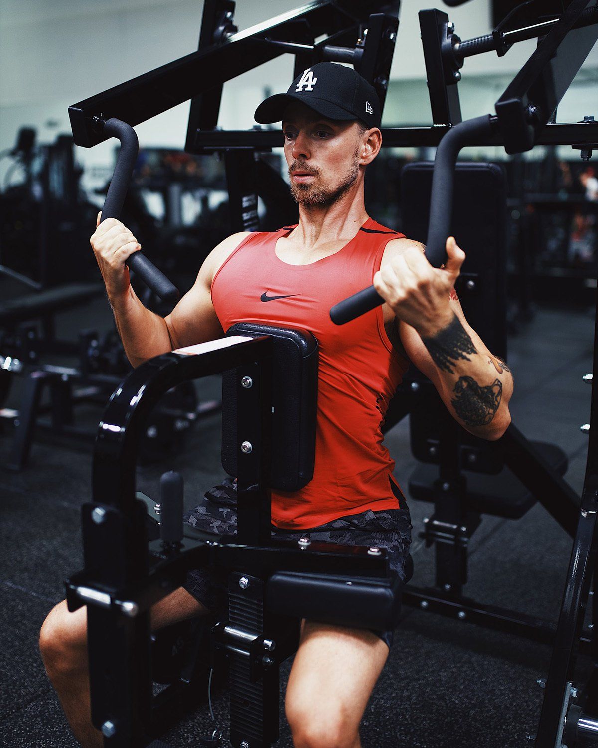 A man in a red tank top is using a machine in a gym