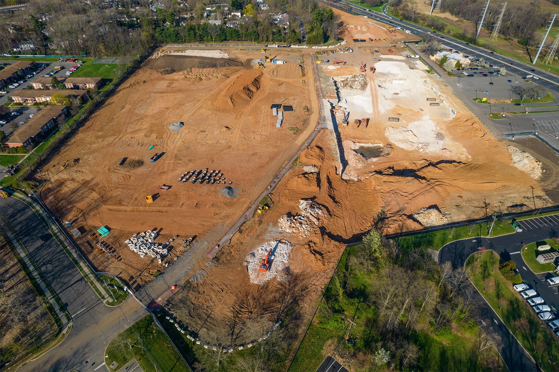 Aerial view of a large construction site, mostly dirt with some foundation remnants and heavy equipment.