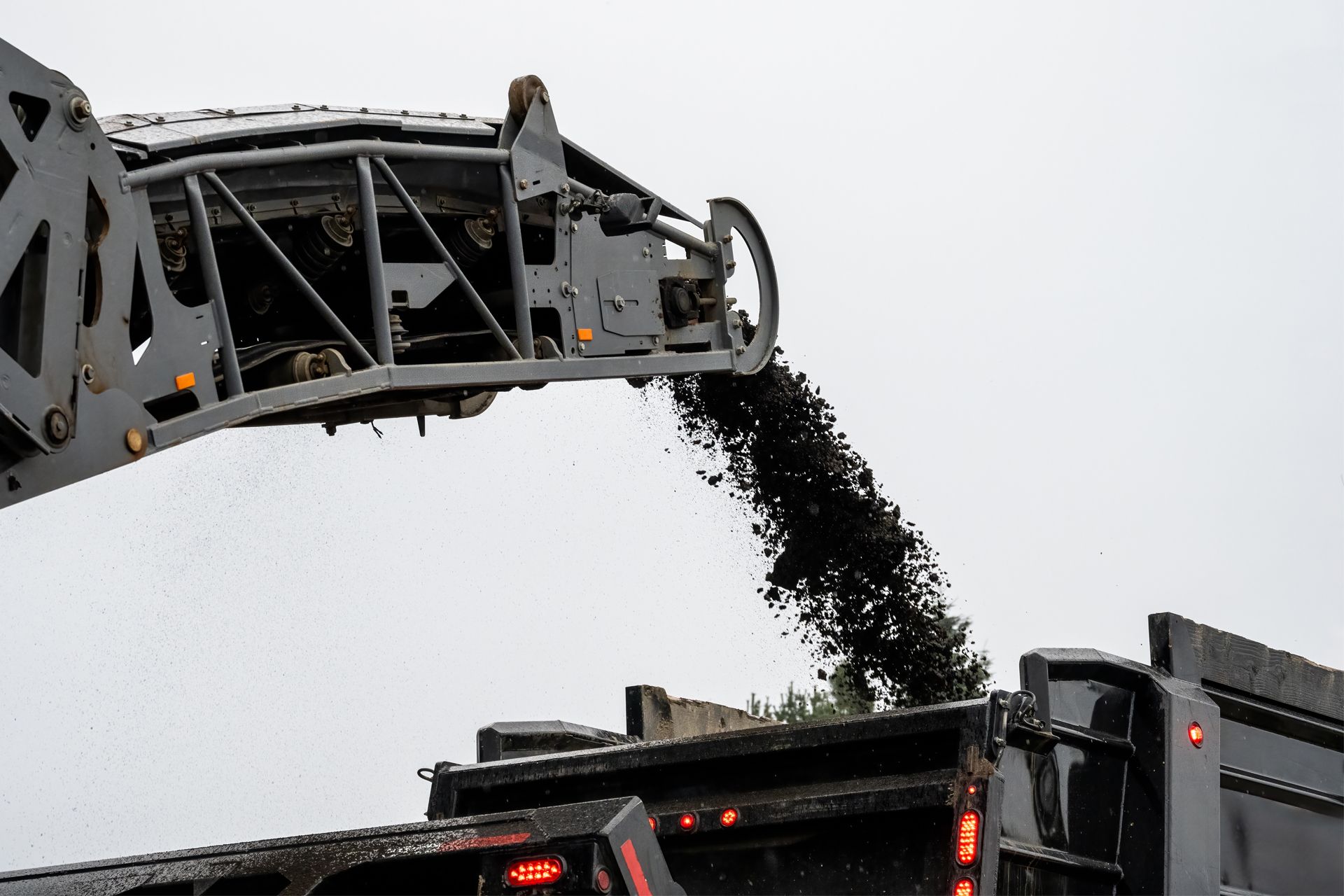 Asphalt milling machine dumping asphalt debris into a dump truck.