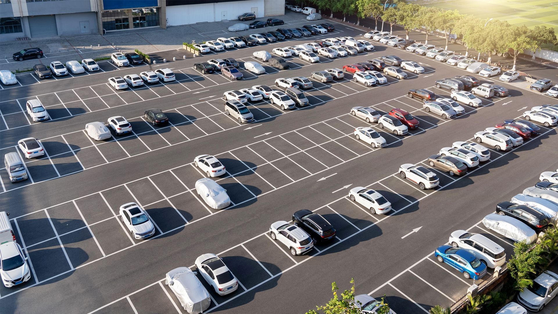 Aerial view of a full parking lot with many cars, with concrete and marked spaces.