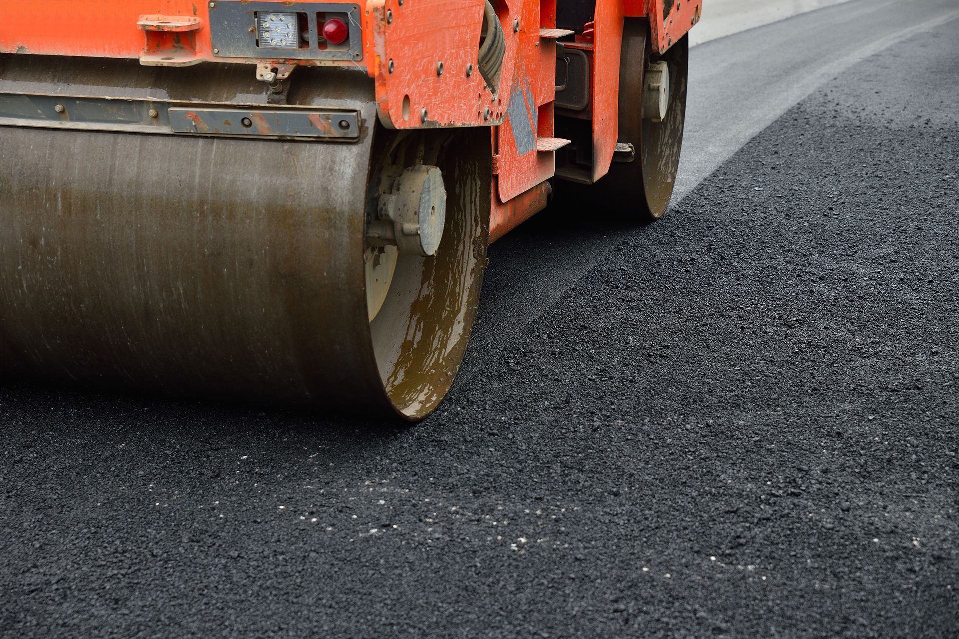 Road roller compacting fresh asphalt.
