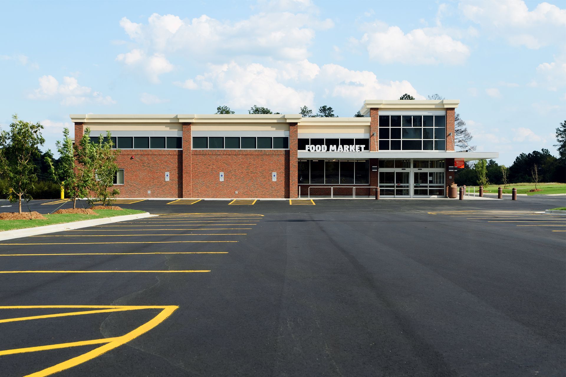 A brick and glass building with a large parking lot, under a blue sky.