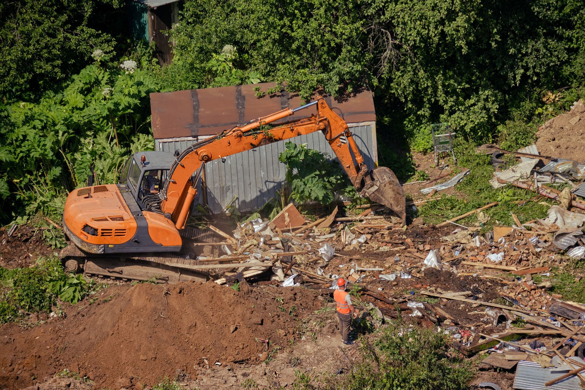 An aerial view of an excavator destroying a house.